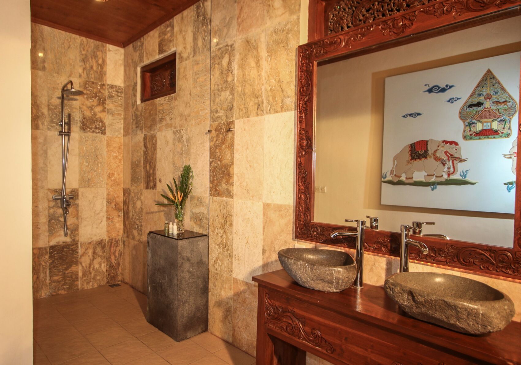 Casa de banho com lavatório de pedra, chuveiro e espelho com moldura decorativa.
