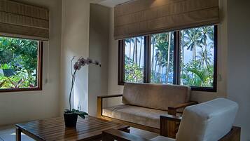 Una habitación con un sofá, una mesa de madera y una orquídea en maceta.