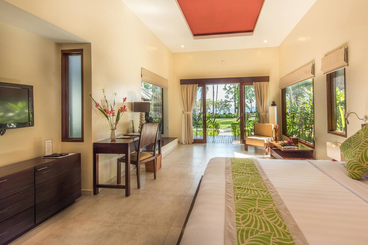 A hotel room with a bed, a desk, a TV, and a view of the outdoors.
