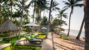Un resort en la playa con sillas de descanso, sombrillas y un paseo de madera.