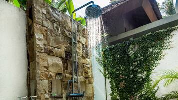 A stone shower enclosure with a built-in seat, a stone wall, and a wall-mounted showerhead.