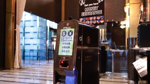 A currency exchange machine with multiple currency options and a sign indicating a money exchange service. - APA Hotel Shibuya Dogenzakaue (Tokyo)