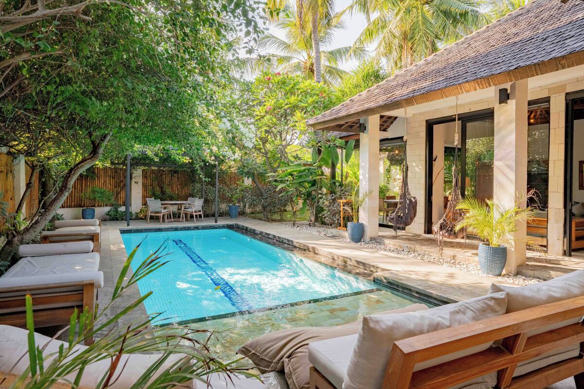 A pool area with lounge chairs, a wooden deck, and a covered seating area.