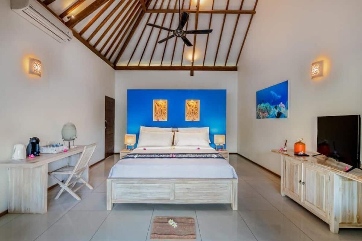 A bedroom with a bed, a desk, a television, and a ceiling fan.