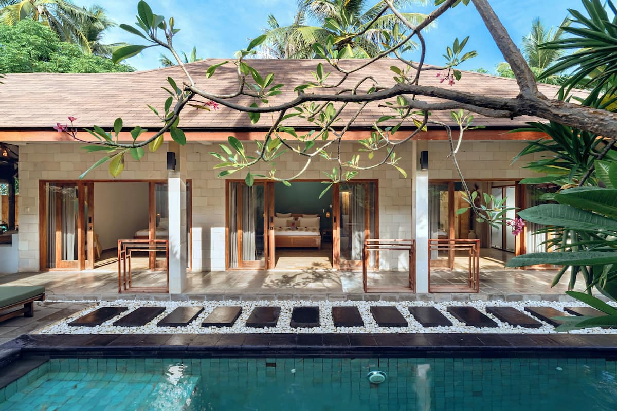 A modern resort with a pool, a bedroom with a balcony, and lush tropical surroundings.