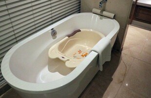 A bathtub with a built-in seat and a small tray.