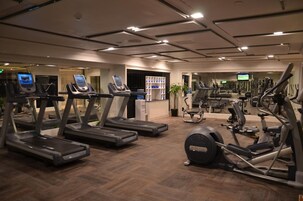 Un gimnasio con cintas de correr, elípticas y equipo de pesas.
