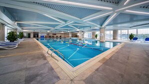 Une piscine intérieure dotée de lignes de démarcation bien visibles, d’un sol carrelé et d’un plafond pourvu d’un éclairage linéaire.