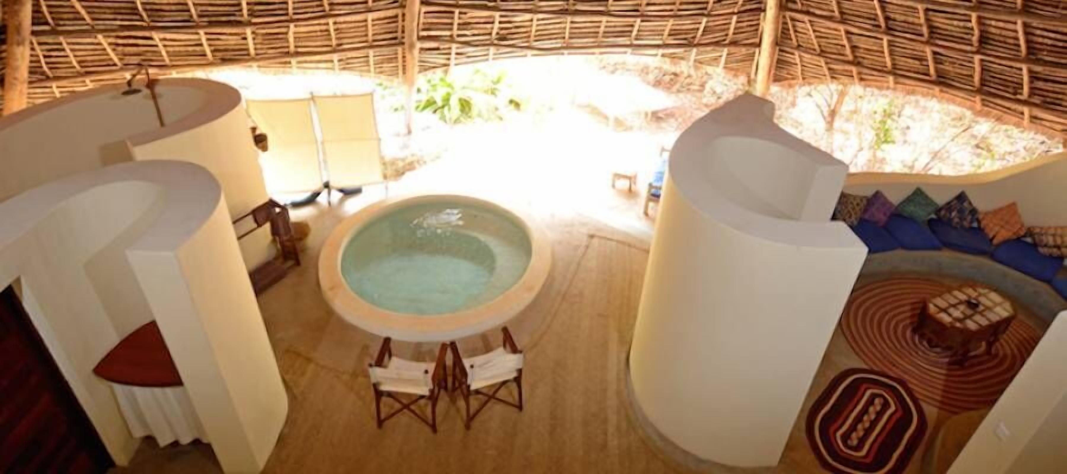 A spa area with a hot tub, seating, and a thatched roof structure.