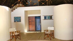 A spacious room with a large bathtub, wooden chairs, and a wooden ceiling structure.