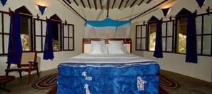Une chambre à coucher avec un grand lit, une chaise et une fenêtre avec des rideaux.