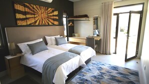 A modern hotel room with a large bed, a desk, and a sliding glass door to the outside. - The Elegant Guesthouse (Windhoek)