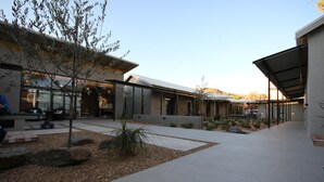A modern building with a covered walkway, outdoor seating area, and a landscaped garden with rocks and plants. - The Elegant Guesthouse (Windhoek)