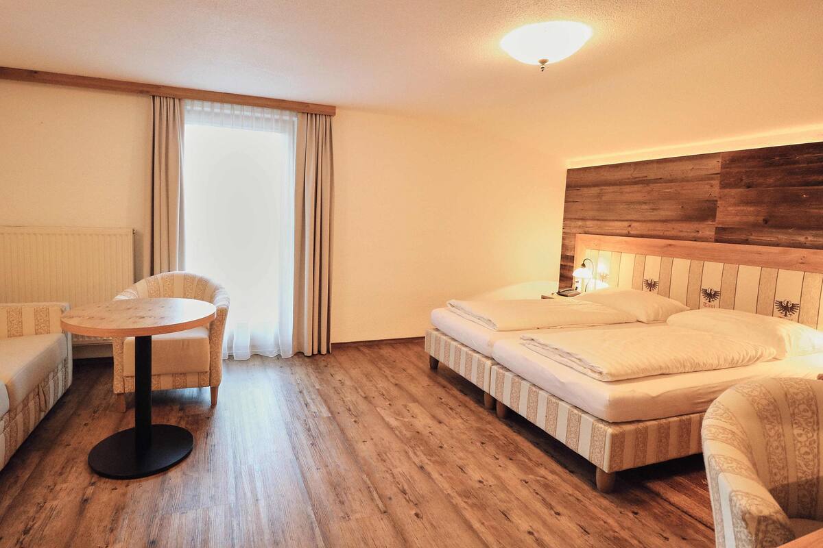 Une chambre d’hôtel avec un plancher en bois, un canapé, une table ronde et un lit doté d’une tête de lit.
