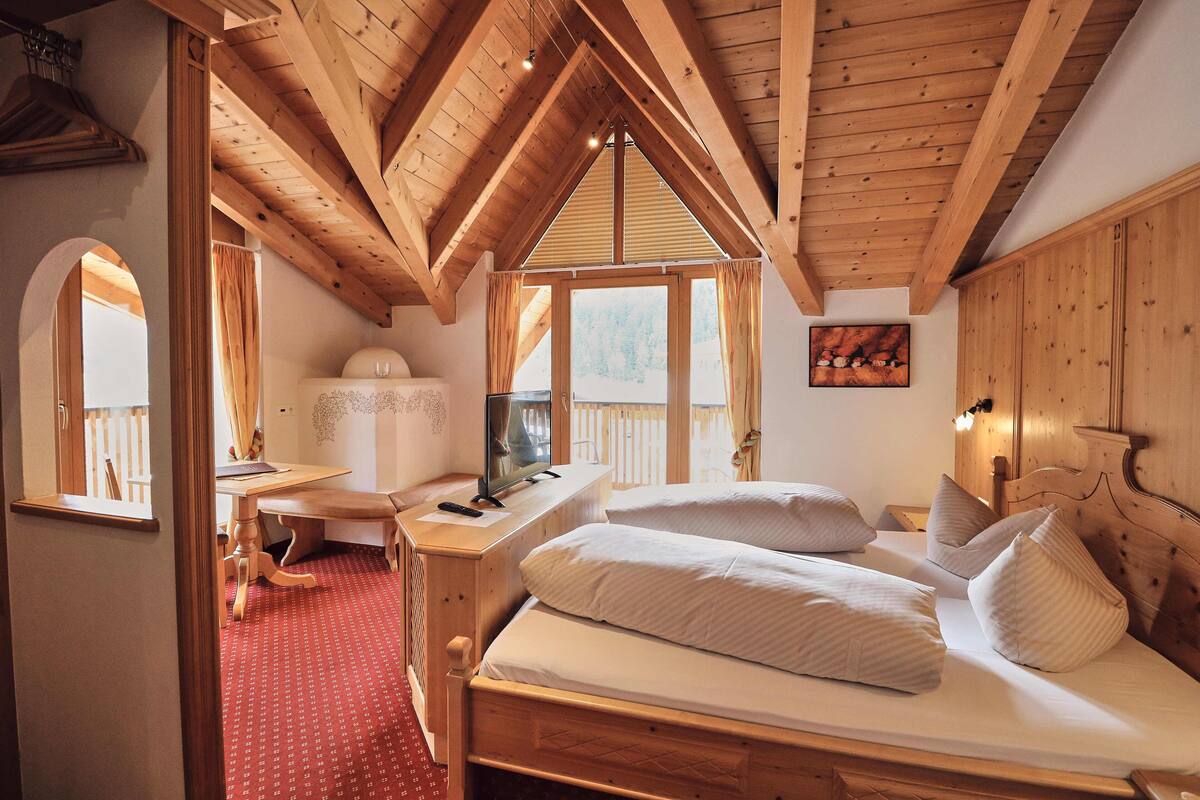 Une chambre avec un plafond en bois, un bureau, un lit avec des oreillers et une fenêtre.