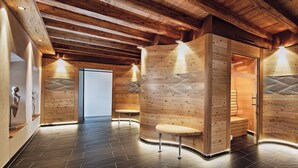 A wooden interior with a curved bench and a wooden wall with a door. - Hotel Traube (Pfunds)