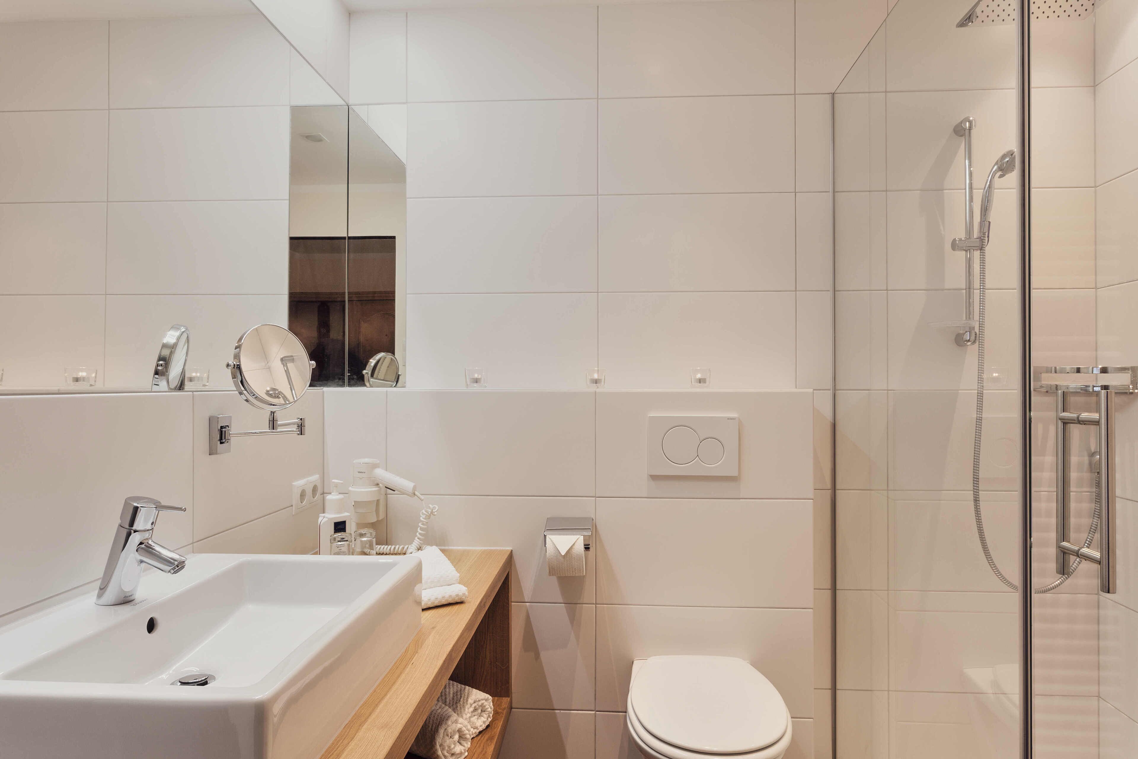 A modern bathroom with a sink, mirror, toilet, and glass-enclosed shower.