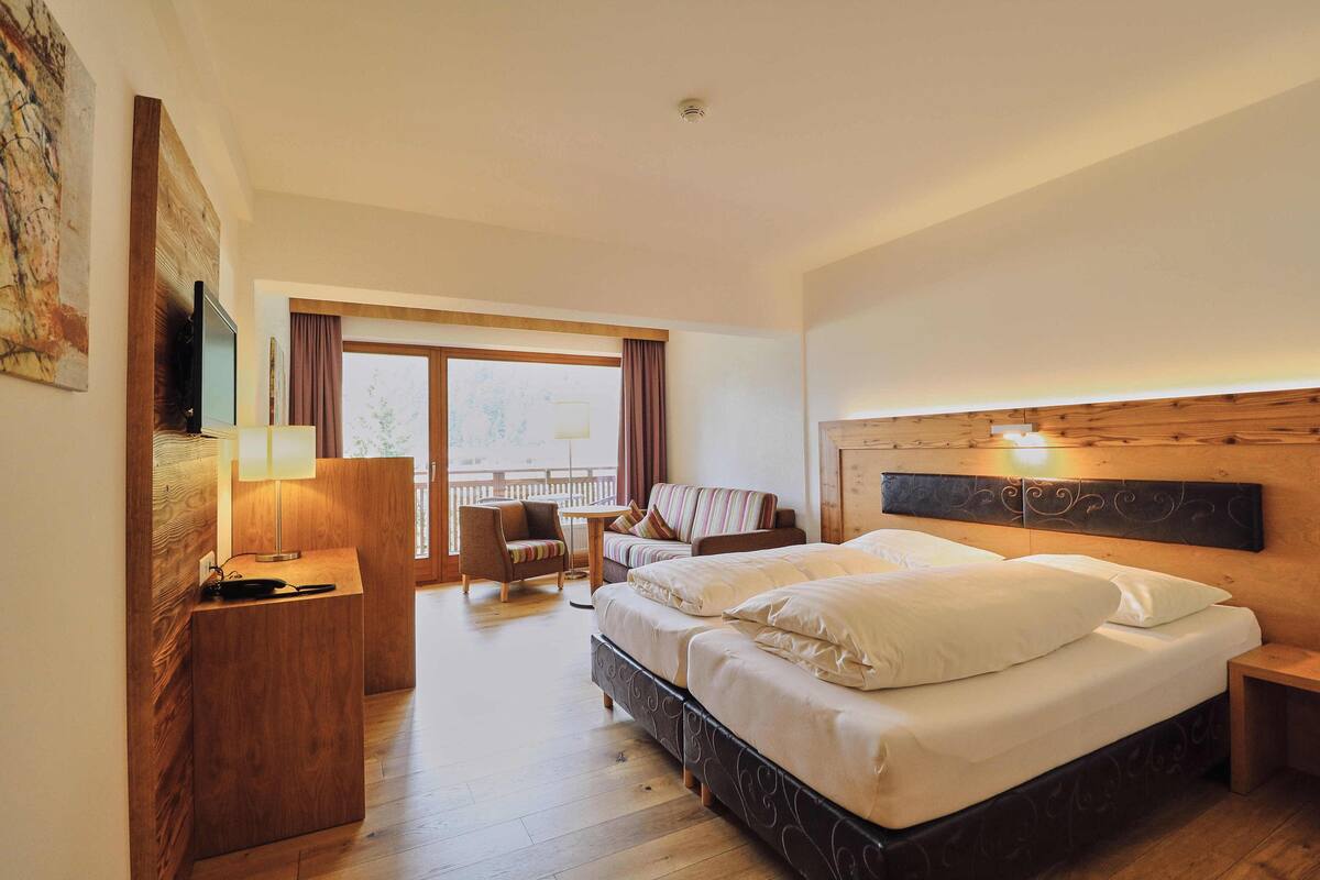 Une chambre d’hôtel avec un grand lit, un bureau, une chaise et un balcon avec vue.