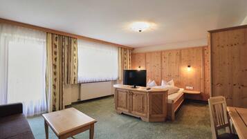 A room with a bed, a TV, a wooden cabinet, a table, and a couch.