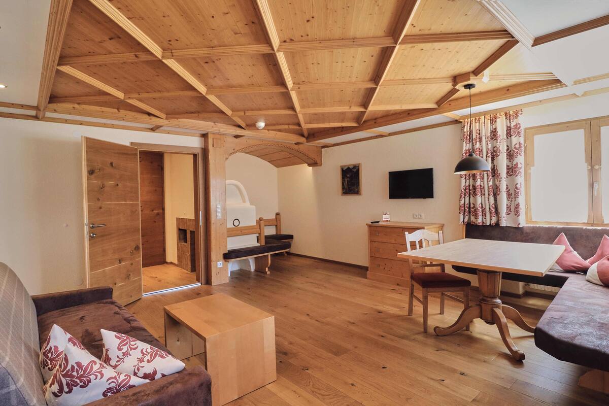 Une pièce spacieuse avec un plancher en bois, une table à manger, un canapé et un téléviseur fixé au mur.