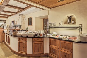 Una cocina amplia con armarios de madera, una isla curva con cubierta de vidrio y diversos alimentos exhibidos en la encimera.