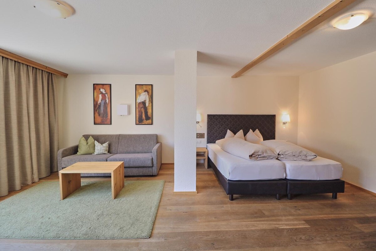 A modern bedroom with a bed, a sofa, and a coffee table.