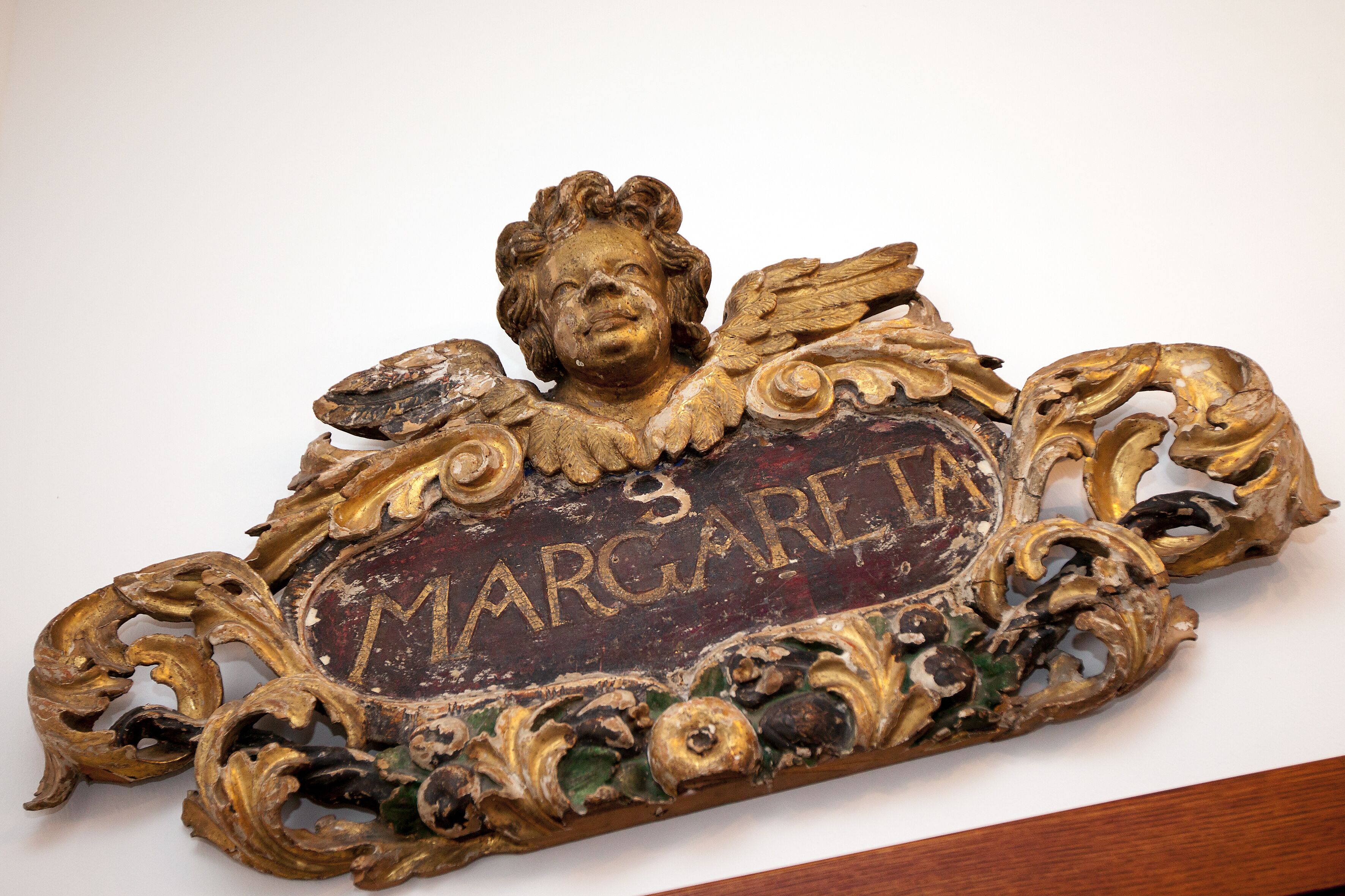 Una targa decorativa con il nome "MARGARET" e motivi ornamentali.