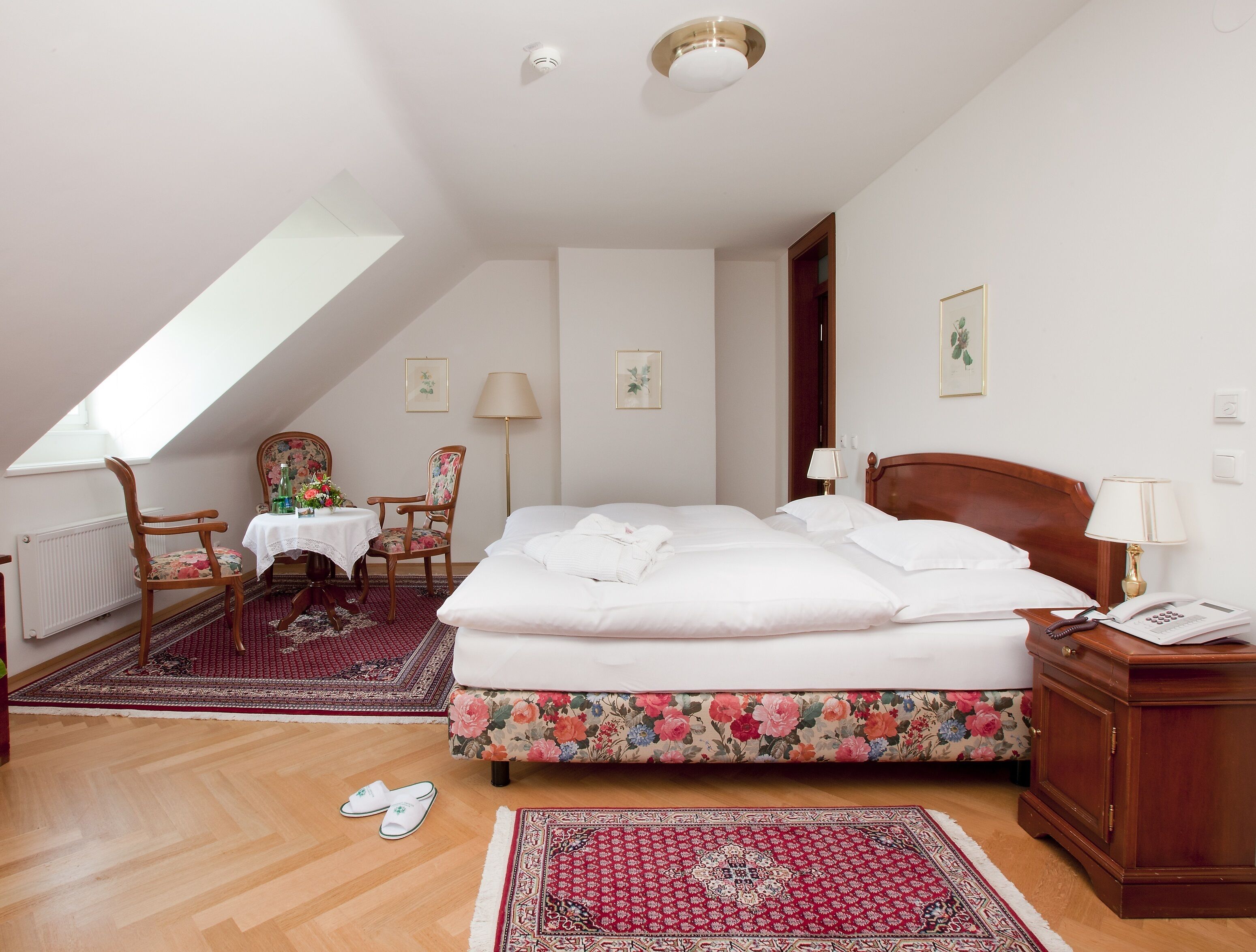 Une chambre à coucher avec un grand lit, une table de chevet en bois, un bureau avec une chaise et un radiateur.