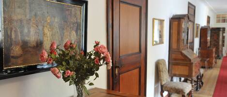 A room with a wooden dresser, a vase of pink roses, and a framed painting on the wall.
