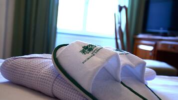 A neatly made bed with a folded towel and slippers.