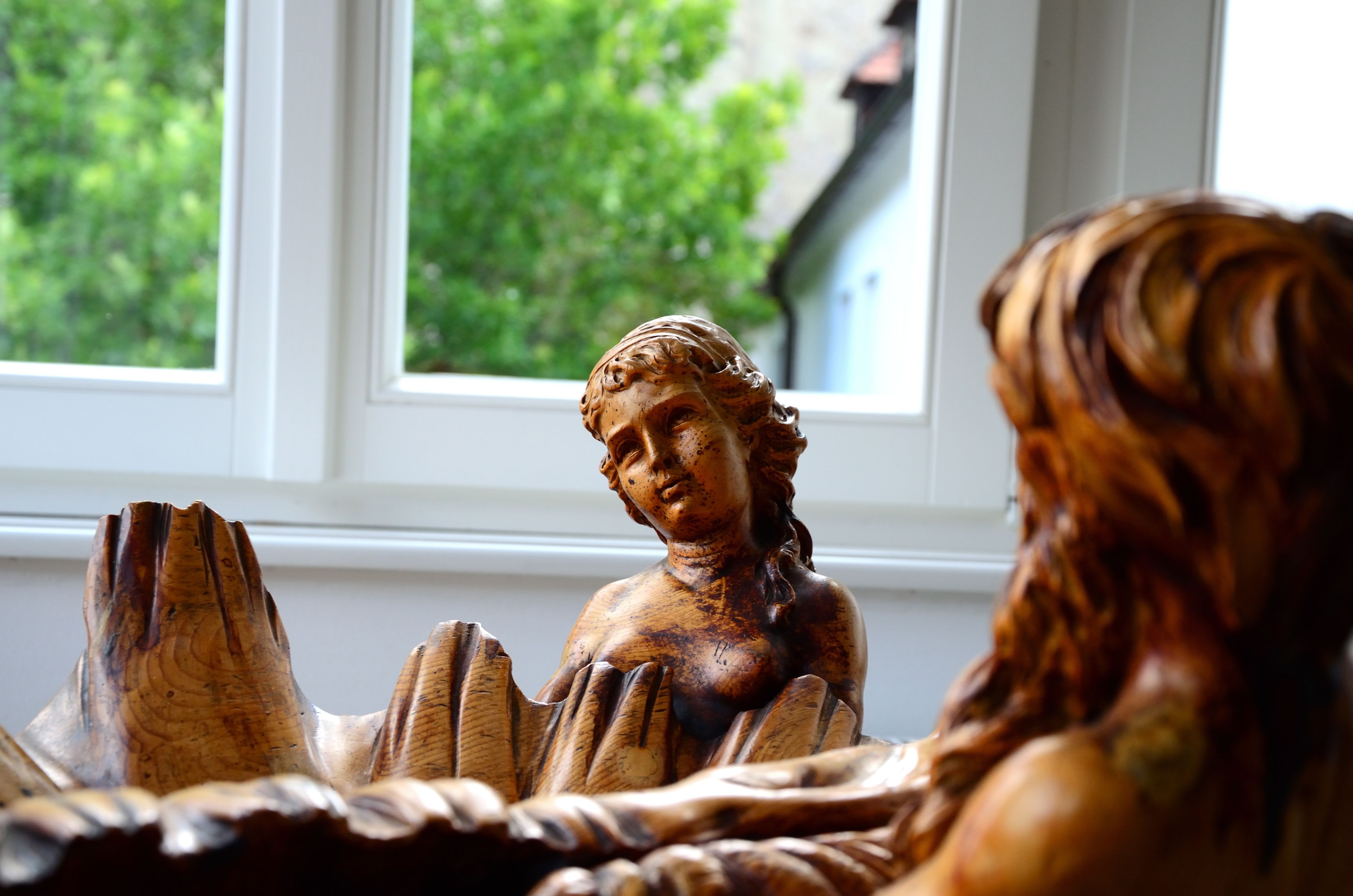 Una escultura de madera de una figura con rostro y manos detallados, sobre una mesa.