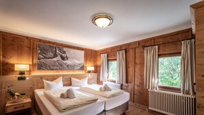 Quarto com painéis de madeira, uma cama de casal, duas mesas de cabeceira, uma luminária fixada na parede e um quadro grande emoldurado.