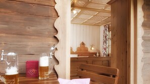 Interior de madeira com uma mesa posta para dois, duas cervejas, um guardanapo xadrez rosa e uma caixa em formato de coração.