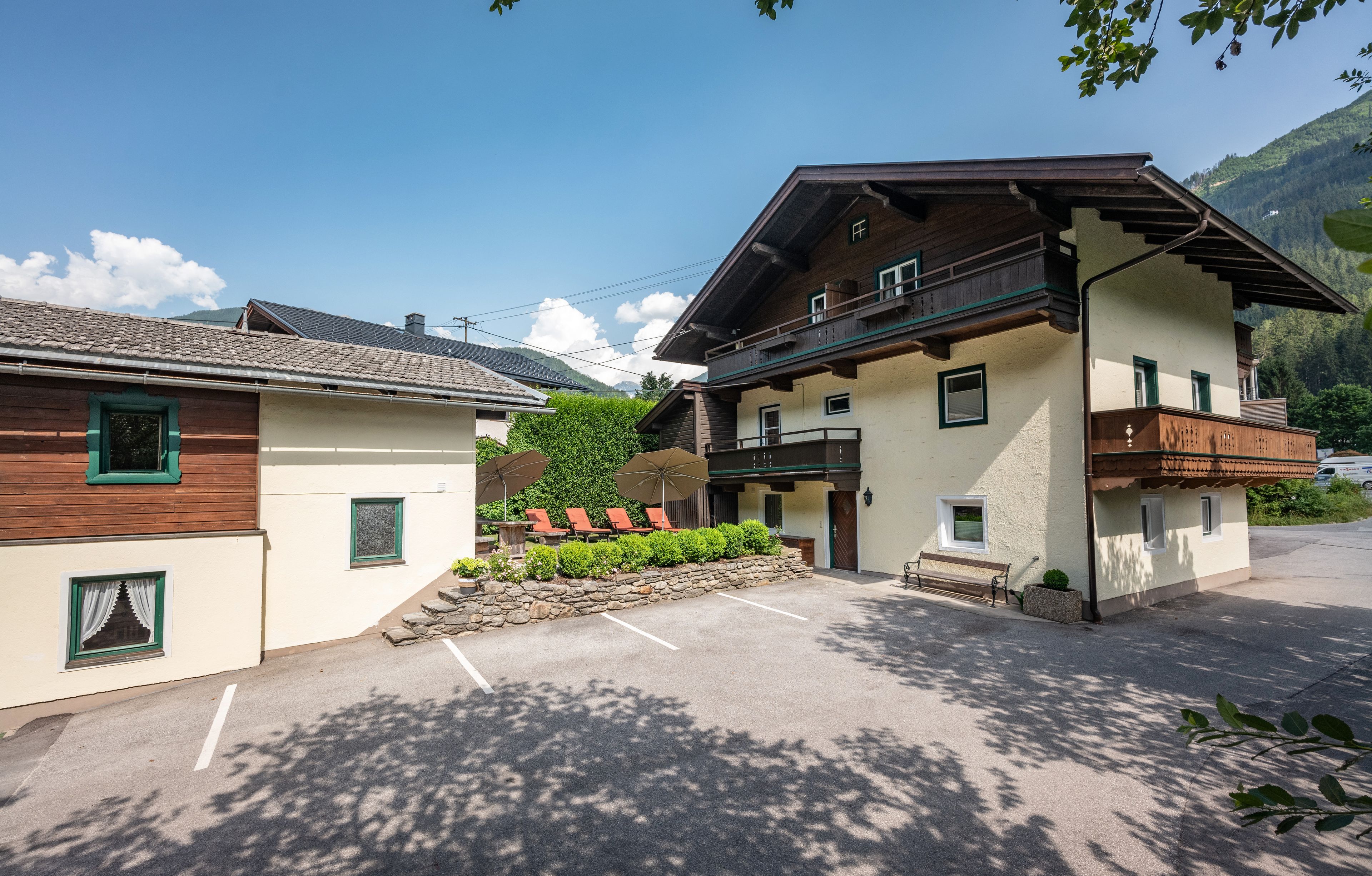 Ein zweistöckiges Gebäude mit Balkon, Steinmauer und einer Reihe von Gartenmöbeln.