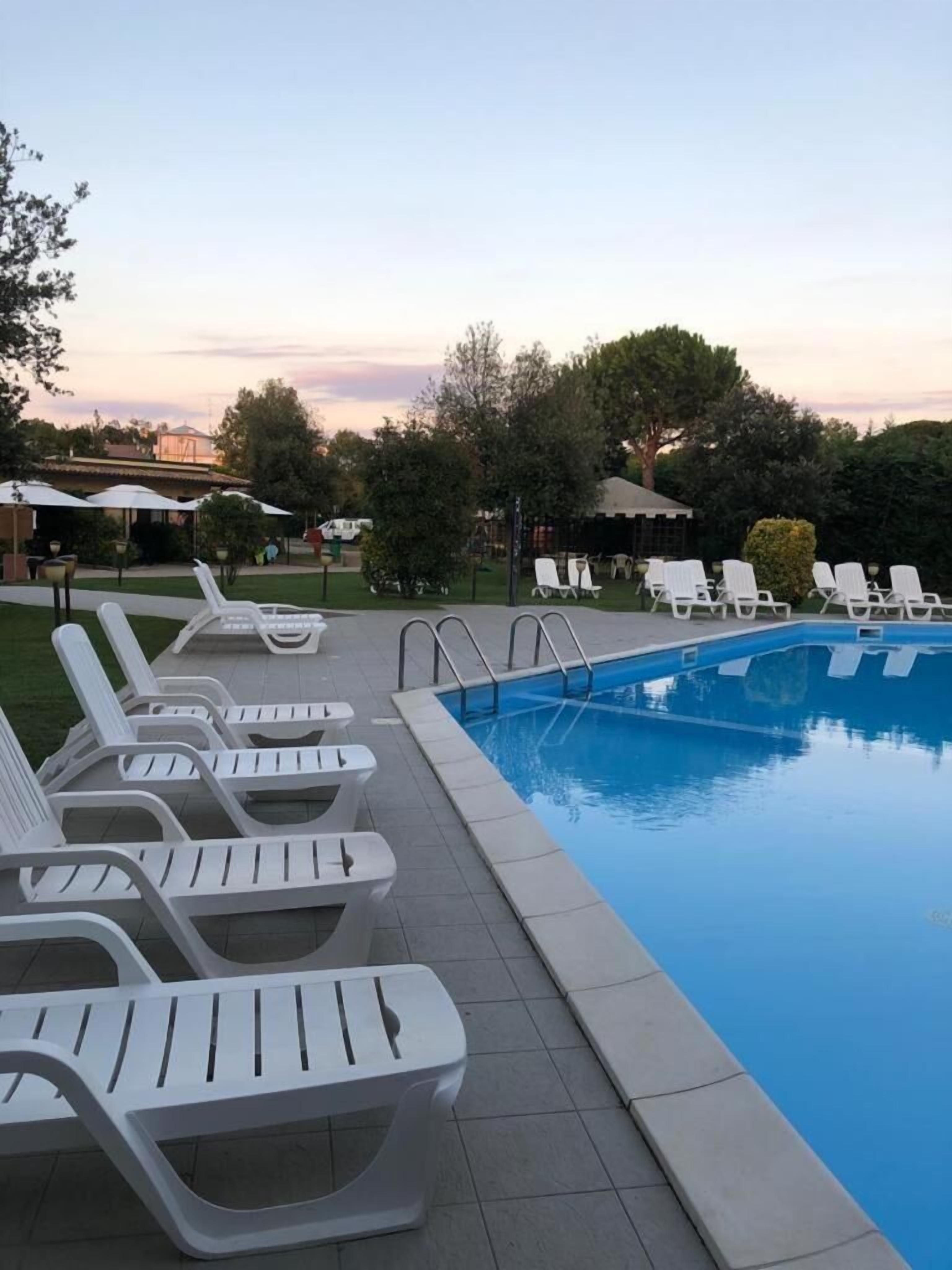 A swimming pool with lounge chairs and a clear sky.