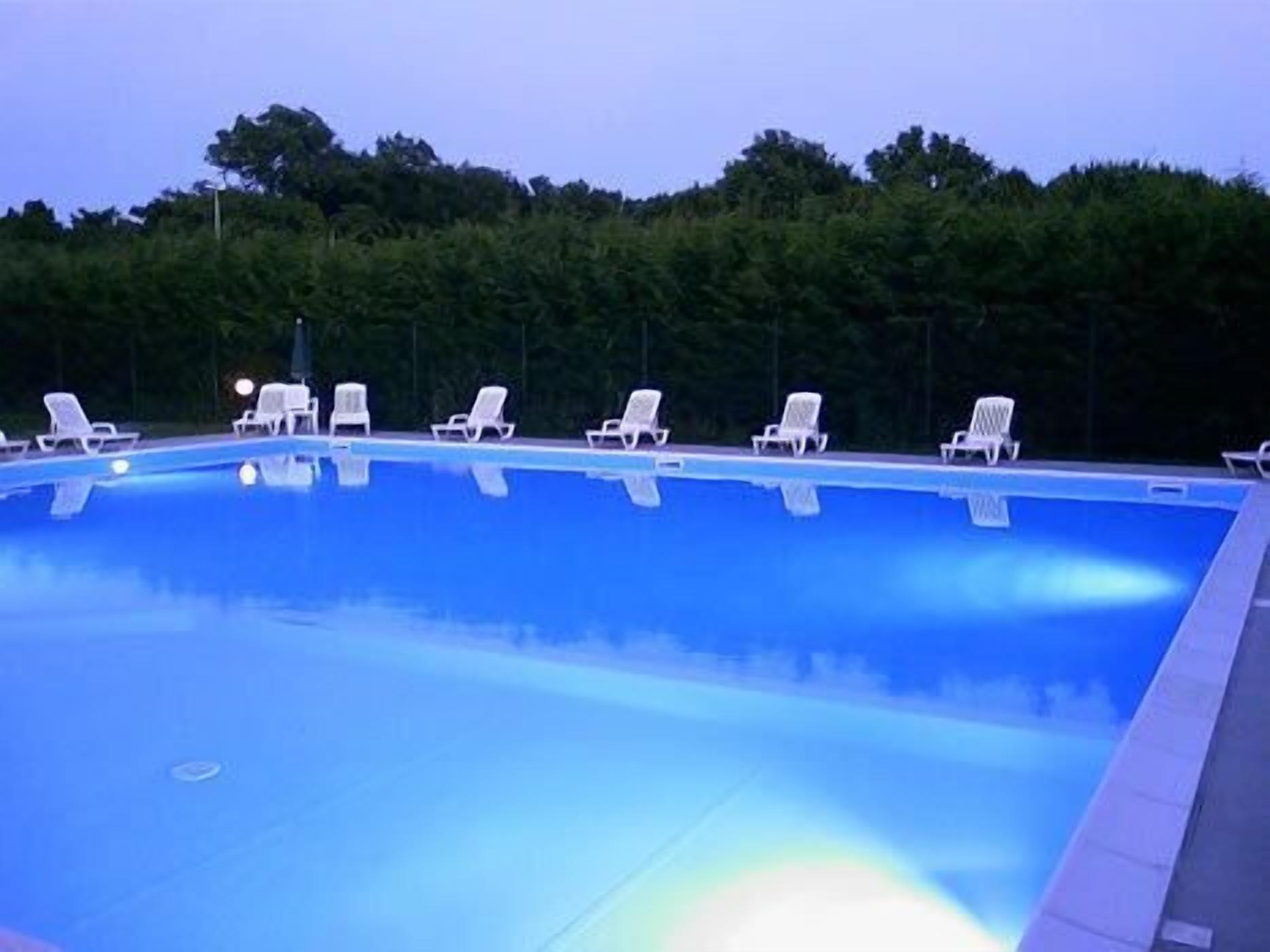A swimming pool with white lounge chairs arranged around it.