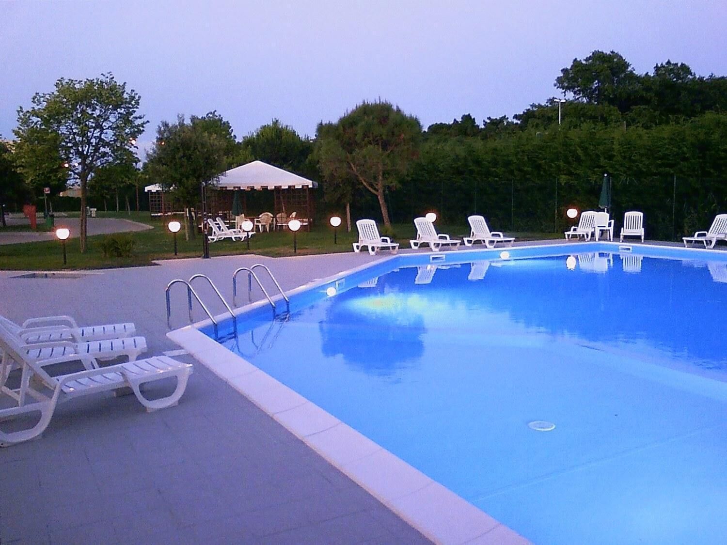 A swimming pool with lounge chairs and a covered seating area.