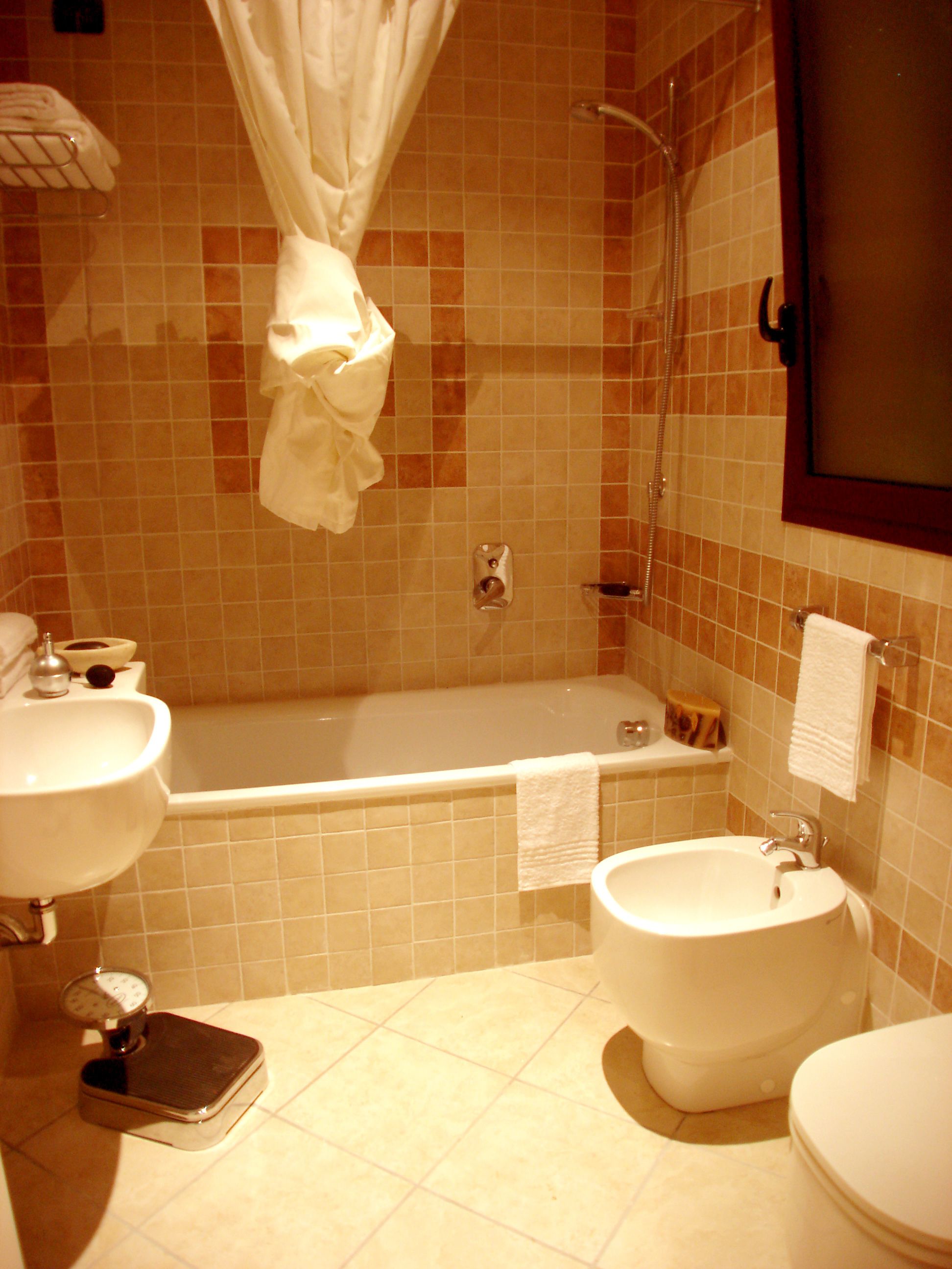 A bathroom with a bathtub, two sinks, a scale, and a toilet.