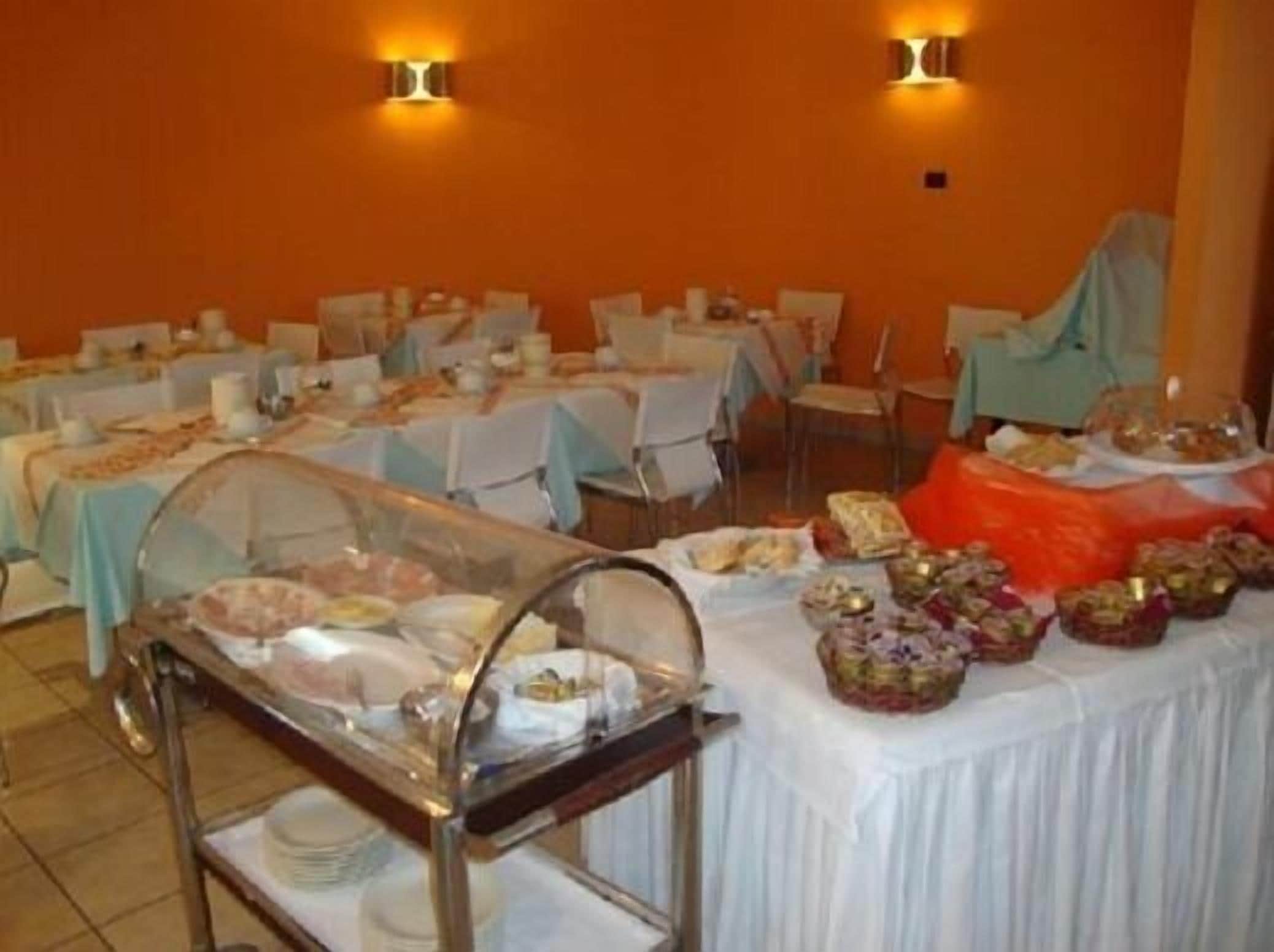 A dining area with tables set for a buffet, featuring a variety of food items and a glass display case.