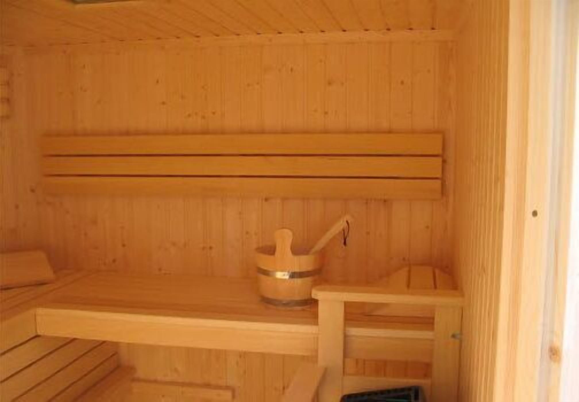 A wooden sauna with benches and a wooden bucket.