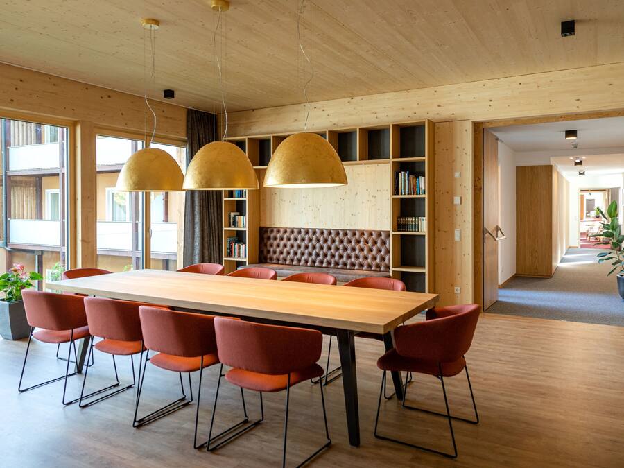 Un comedor moderno con una mesa de madera, sillas rojas e iluminación colgante.