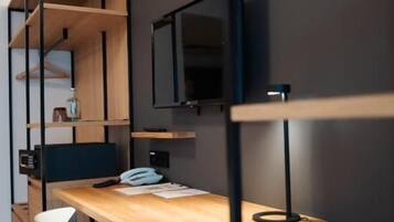 Una habitación moderna con un escritorio de madera, una silla, televisor y estanterías empotradas.
