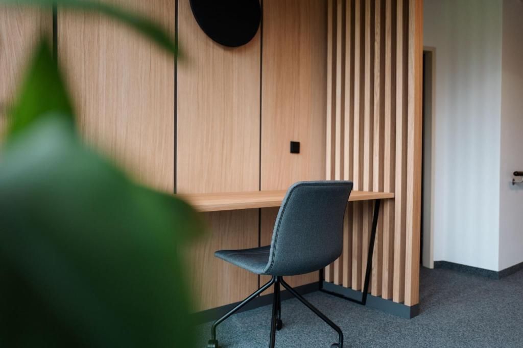 Un espacio de oficina moderno con un panel de pared de madera, una silla de oficina gris y un escritorio pequeño.