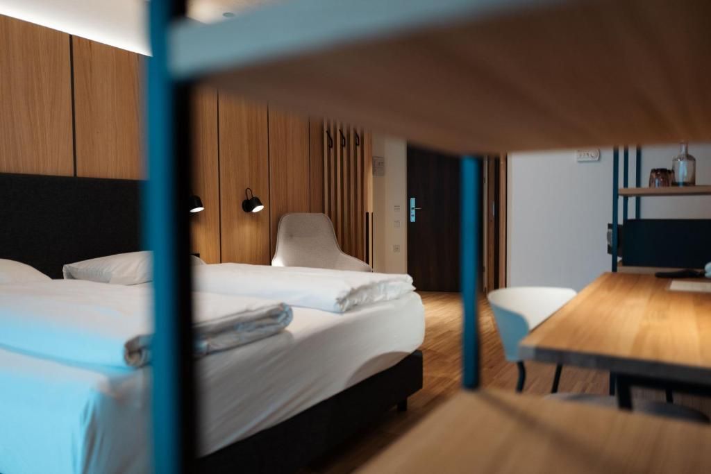 A hotel room with a bunk bed, a desk, and a chair.
