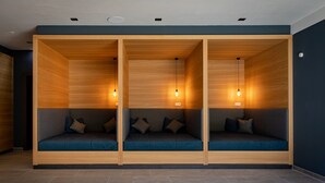 A modern interior with three wooden seating areas, each with a cushioned bench and a hanging light fixture.