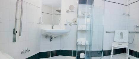 A modern bathroom with a glass shower enclosure, a white sink, and a toilet with a safety seat.