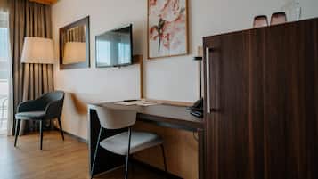 Quarto moderno com escrivaninha de madeira, duas cadeiras, uma TV e um armário.