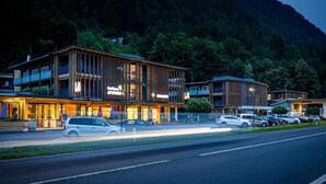 A modern hotel with a two-story structure, outdoor seating area, and a parking lot.