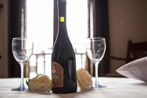 Una botella de vino sobre una mesa con dos copas de vino vacías y una flor.
