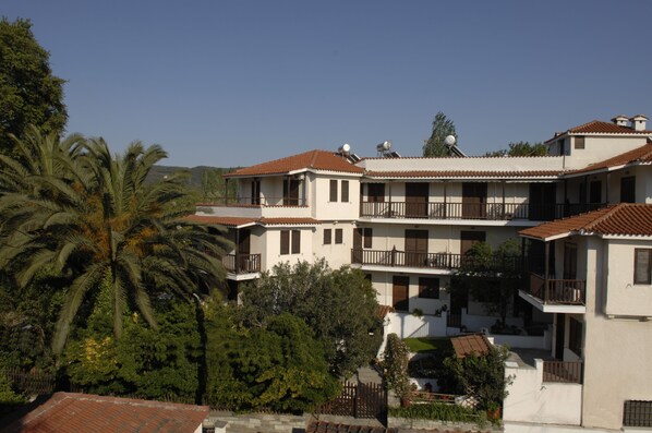 Un edificio de varios pisos con balcones, antenas parabólicas y una palmera en primer plano.
